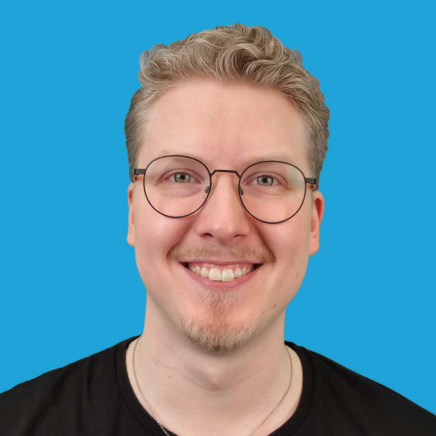 Antero Jokinen, hieman yli kolmekymppinen mies, silmälasit päässä, musta paita, sininen taustaväri